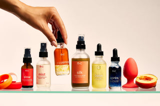 Collection of Peach and Cream wellness produt bottles with a hand reaching for one on a neutral background