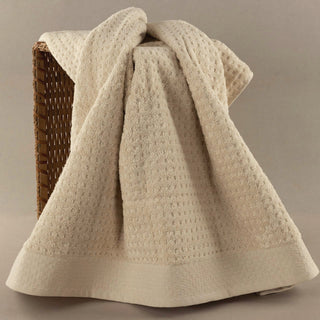 A folded cream knit towel on a warm neutral background