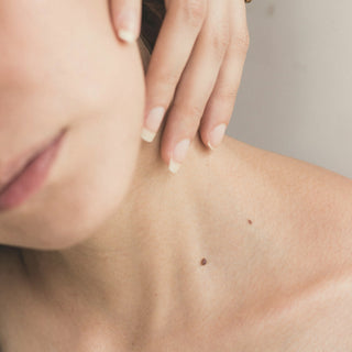 A hand resting on a bare shoulder and neck in soft light