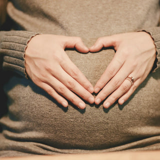 Hands shaping a heart over a pregnant belly