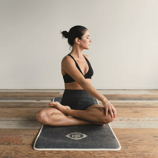 A woman sitting cross legged on a yoga mat