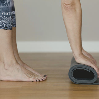 bare feet beside a rolled exercise mat