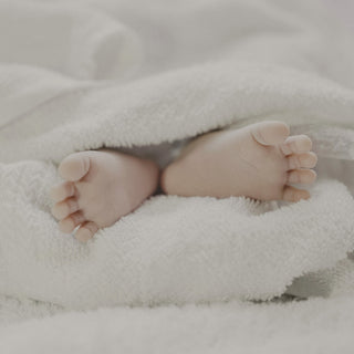 A baby's feet peeking out of a soft white towel