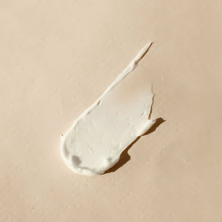 A swipe of white balm on a beige surface