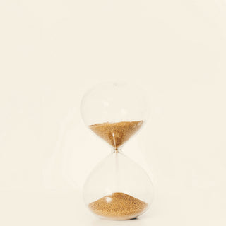 An hourglass with golden sand on a white surface