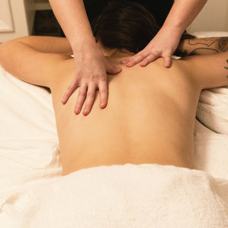 Hands giving a back massage over a white towel