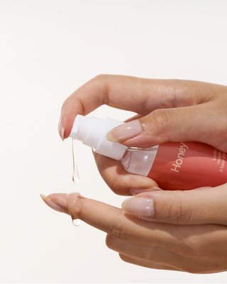 A woman pouring Peach and Cream personal lubricant on her finger