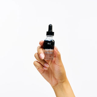 Hand holding a bottle of Peach and Cream 'après' shaving aftercare with a dropper against a white background