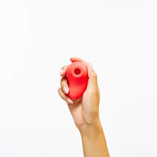 Hand holding Peach and Cream 'aura' vibrator on a white background
