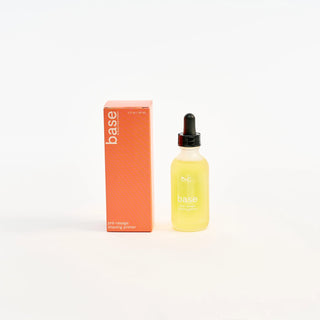 Peach and cream shaving primer bottle with dropper and orange box labeled 'base' on a white background