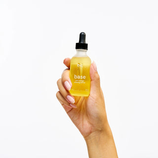 Hand holding a bottle labeled Peach and Cream shaving primer 'base' against a white background
