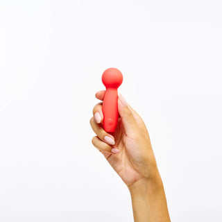 Hand holding Peach and Cream 'Cakepop' vibrator against a white background