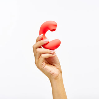 Hand holding Peach and Cream 'Glow' vibrator on a white background
