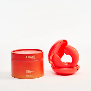 Red cylinder packaging with Peach and Cream 'Glow' vibrator in his charging case a white background