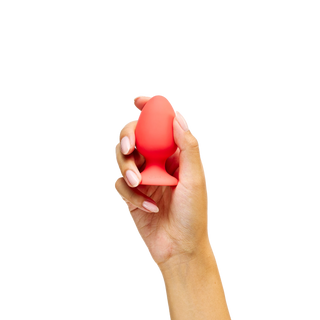 Hand holding a red Peach and Cream Uno Plug 